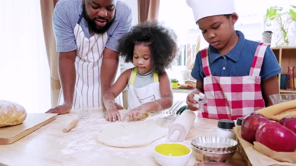 Happy joyful African American family having fun dancing in the kitchen, cooking together at home