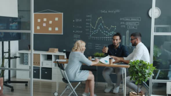 Zoomin of Businesspeople Working in Office Walking with Papers and Talking at Table alt