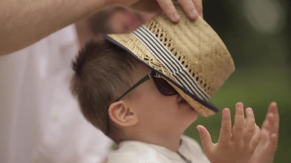 Caring Parent Pulling the Headwear Off His Son Face