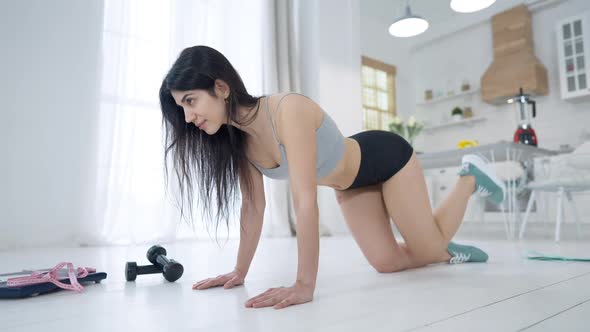 Wide Shot of Young Confident Sportive Woman Raising Leg Doing Kickbacks Exercise alt