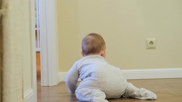 Baby toddler reaches into the electrical outlet on the home wall with his hand.