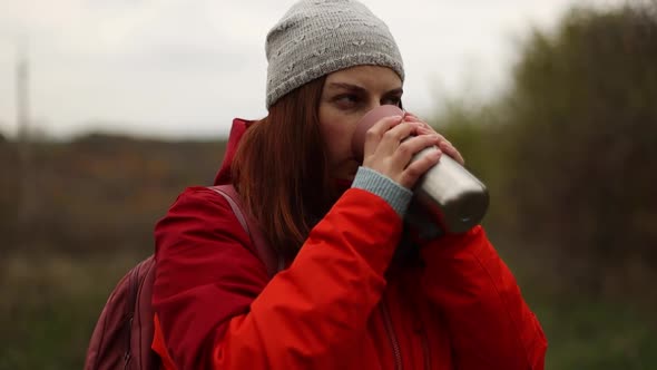 Close Up of a Young Hiker Woman Drink Hot Tea From Thermos in Autumn Forest