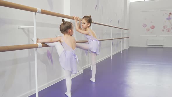 Two Cute Little Ballerinas Stretching at Ballet School Together