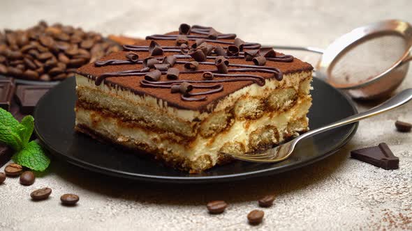 Portion of Traditional Italian Tiramisu dessert and pieces of chocolate bar alt