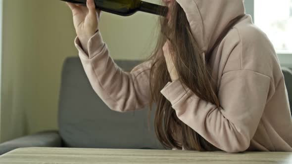 An Unkempt Woman is Drinking Wine From a Bottle Alone alt
