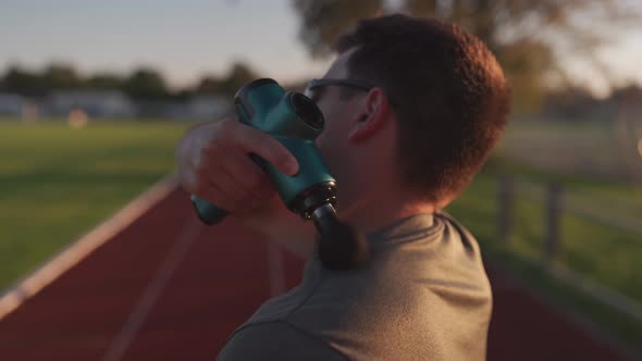 An Athlete Massages with a Percussion Therapy Gun to Relieve the Pain of Muscle Aches After a alt