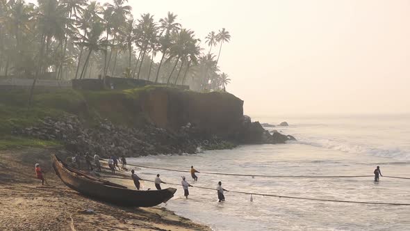 Local people working with traditional fishing nets, Kappil Beach, Varkala, India, at dusk alt