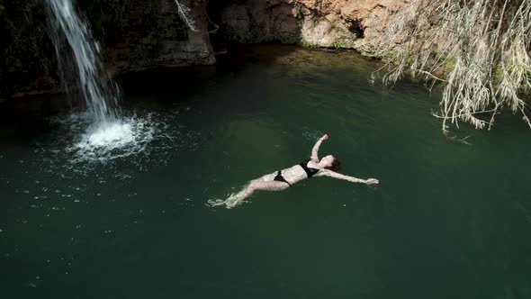 Girl Swimming Near Exotic Waterfall