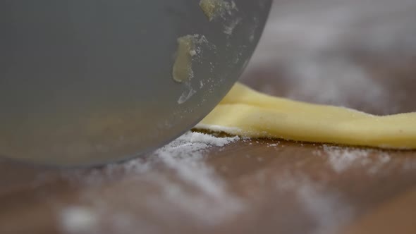 Pizza Cutter Rolling And Cutting Faworki Dough With Flour. extreme close up, slow motion alt