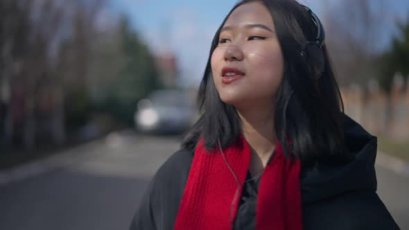 Closeup Portrait of Joyful Young Asian Woman Walking in Slow Motion Dancing to Music in Headphones alt