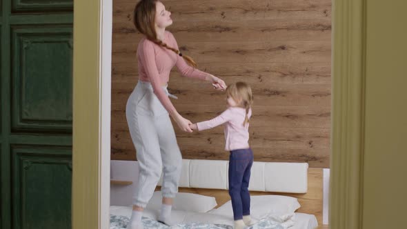 Happy Funny Family Mother and Child Kid Daughter Dancing Jumping on Bed Listening Music at Home alt
