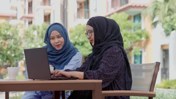 Two good-looking Muslim women working outside the slogan work form home