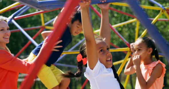 Trainer assisting schoolkids while playing in playground alt