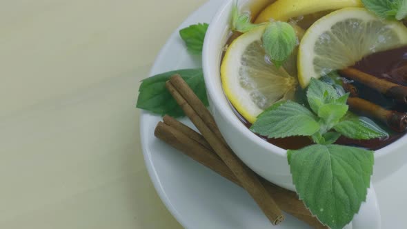 Black and Green Tea with Lemon Cinnamon Sticks and Mint Leaves Rotating alt