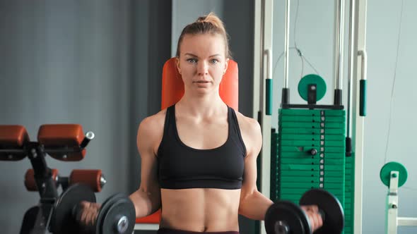 Sporty Young Woman Exercising with Dumbbells in the Gym alt