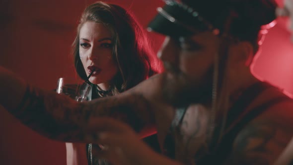 Young People in Bdsm Outfit Sitting in Bar and Drinking Alcohol alt