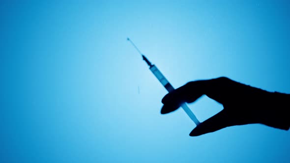 Making Vaccination Injection Shadow of Doctor Holding Syringe Closeup alt
