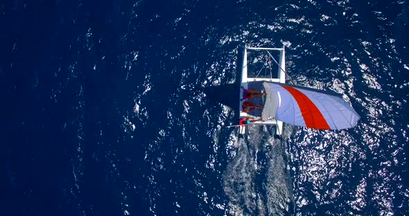 Aerial drone view of a man and woman sailing on a boat to a tropical island. alt
