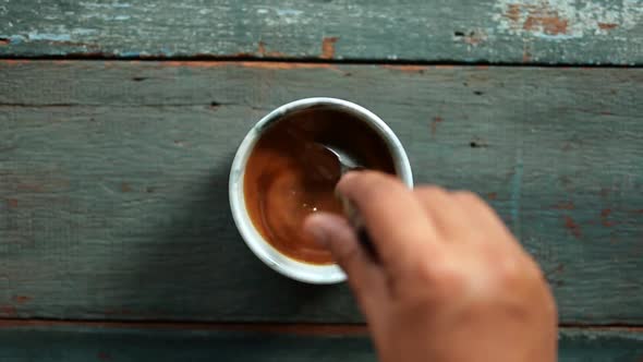 Hand Stir Coffee and Milk in Cup, Hot Drink Mixing. Overhead Table Top Shot