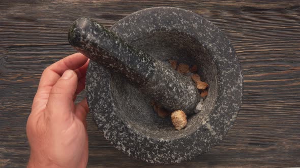 Top View of Hands Putting Sea Salt and Brown Sugar Into the Grey Stone Mortar alt