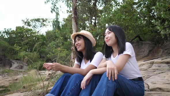 Lgbt lesbian women couple sitting talking together on the rock alt