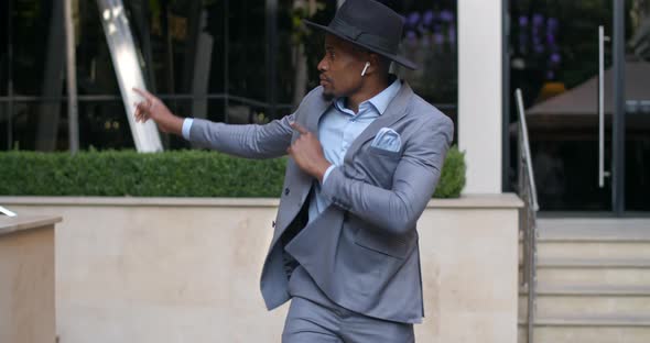 Happy African American Businessman with Wireless Headphones Dancing and Smiling at Street