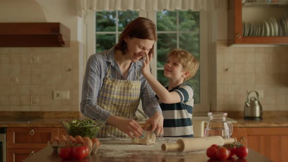 30s Mother and Son Kneading Dough Together Standing in the Kitchen alt