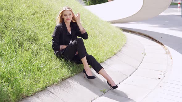 Positive Businesswoman Sitting on Grass alt