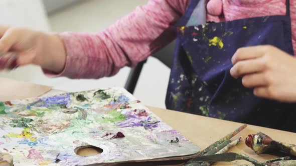 Cropped Shot of a Girl Squeezing Paint From a Tube on To a Palette alt
