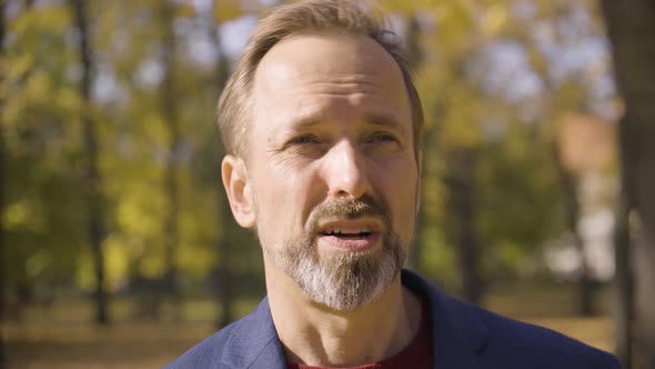 A Middleaged Handsome Caucasian Man Talks to the Camera in a Park in Fall  Closeup