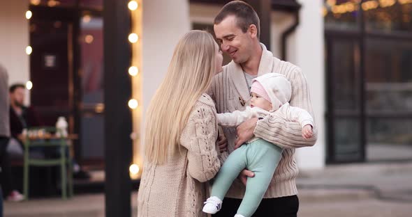 Happy Family with Cute Baby Relaxing in Evening Outside