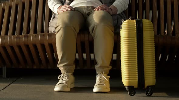 Legs of a Man Sitting on a Bench Waiting for His Flight