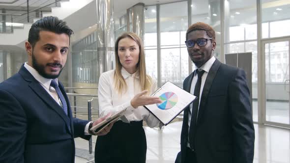 Financiers discussing diagram in hall of contemporary building