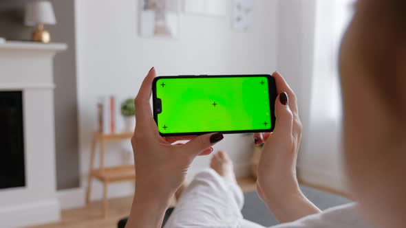 Young Female Using Smart Phone Sitting On Sofa At Home