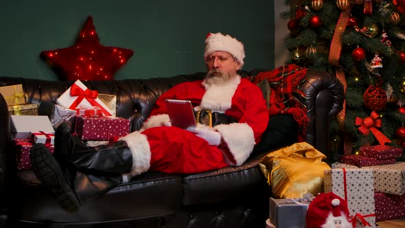 Santa Claus Communicates By Video Call Using Tablet alt