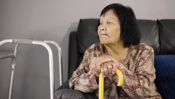 Senior woman with cane resting and sitting on couch in living room