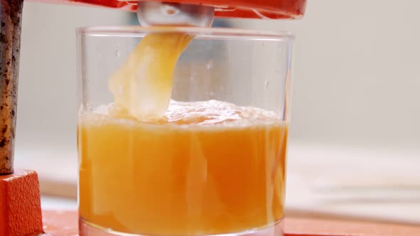 Super slow motion of fresh orange juice squeezed using a manual squeezer alt
