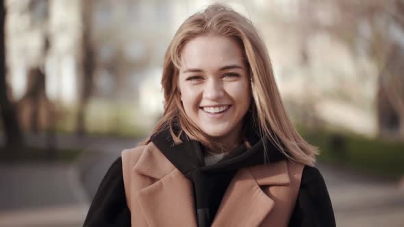 Portrait of Cheerful Contented Woman Having Fun While Walking in City Garden in Sunny Afternoon alt