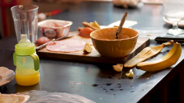 Messy Table And Baby High Chair After Feeding The Baby At Home Kitchen. close up, tilt down alt