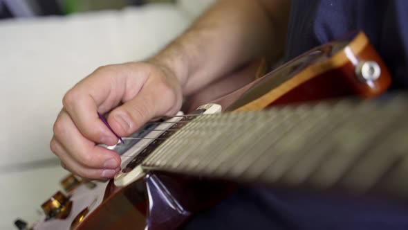 the Hand of a White Guitarist Alternately Strikes the Metal Strings of an Electric Guitar with a alt