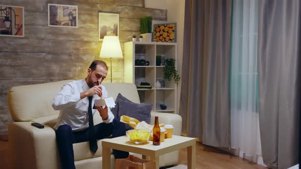 Businessman Sitting on Couch Eating Takeaway Noodles From Box alt