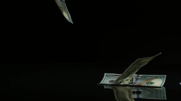 American $100 Bills Falling onto a Reflective Surface alt