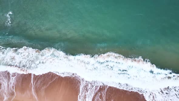 Aerial Top View of Ocean Waves Reaching Beach Shore. Drone Footage. alt