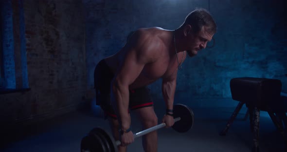 Muscular Man Does Deadlift and Curls with a Heavy Barbell