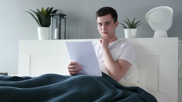 Pensive Man Reading Agreement in Bed alt