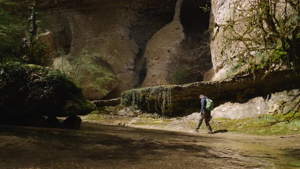 Male traveler with backpack walking near the river or stream in a tropical cave