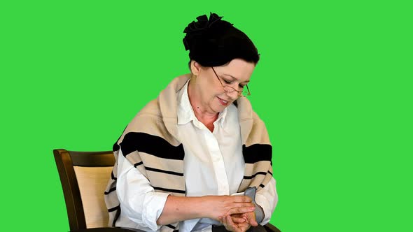 Mature Woman Using Blood Pressure Measurement Device and Feeling Good on a Green Screen Chroma Key alt