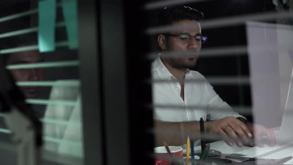 Asian businessman staying overtime late at night seriously working on computer in the office