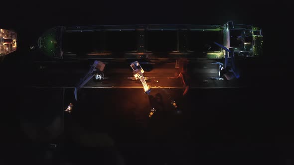 View From a Drone Vertically Down to Cargo Cranes Working in the Port at Night alt