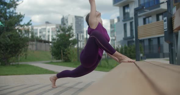 Athletic Woman Does Twine on the Bench in a Public Yard, Stretching Exercises in the Urban